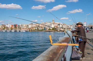 Galata Köprüsü 'nde kimliği belirsiz bir Türk balıkçı ve İstanbul' da arka planda Galata kulesi