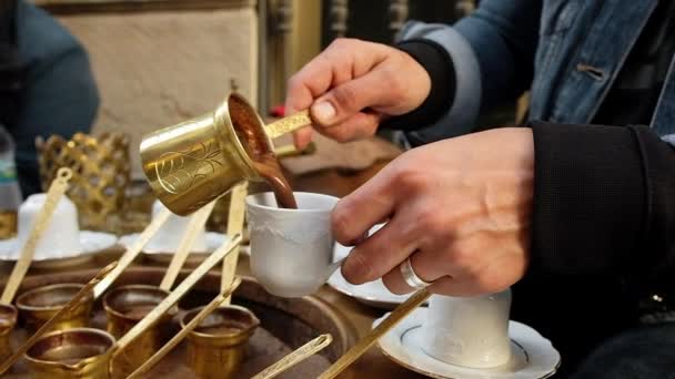Vrouwen handen gieten traditionele Turkse koffie in een kopje. — Stockvideo