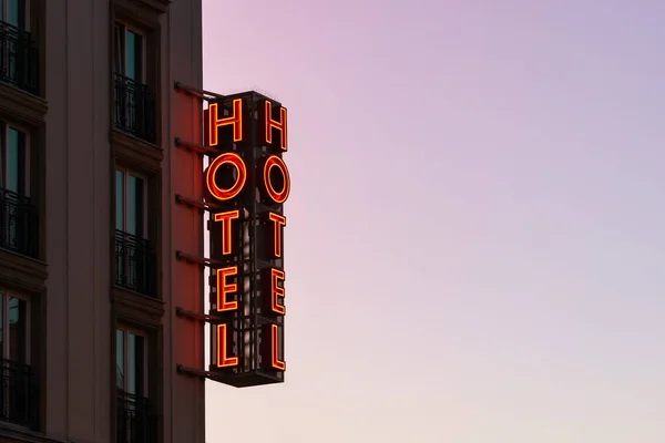 Neon hotel felirat az épület sarkában a naplemente égbolttal szemben — Stock Fotó