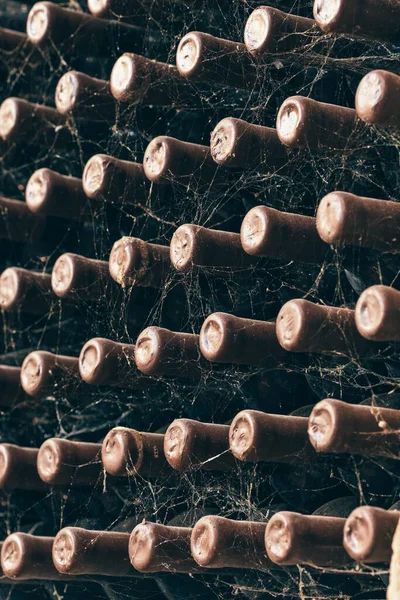 Wine bottles stacked up in old wine cellar close-up background — Stock Photo, Image