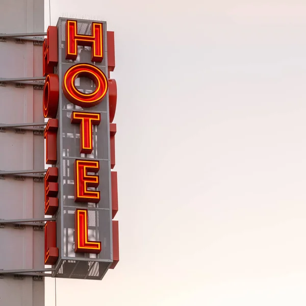 Neon hotel sign on the building corner against the sunset sky — Stock Photo, Image