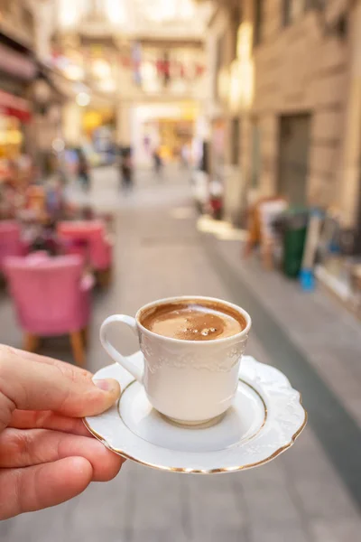 Mens hand holding cup of the traditional Turkish coffee close-up in Istanbul
