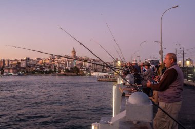 Galata Köprüsü 'nde kimliği belirsiz bir Türk balıkçı ve İstanbul' da arka planda Galata kulesi