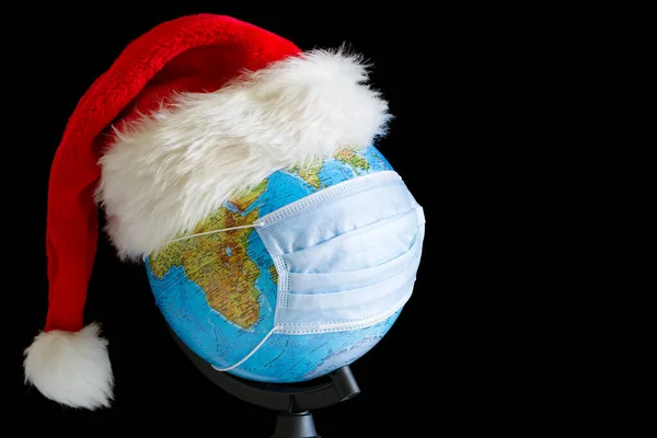 Earth globe in xmas hat and sterile medical mask at black background — Stock Photo, Image