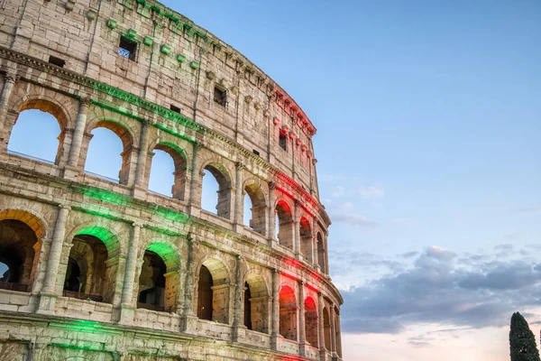 The famous Colosseum in Rome illuminated in Italian flag tricolore at twilight — Stock Photo, Image