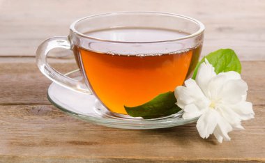 Cam bardak çay ile ahşap masaya Yasemin çiçek