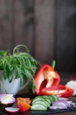 Eski bir ahşap masa üzerinde bir kesme tahtası üzerinde bir salata için taze sebze dilimlenmiş