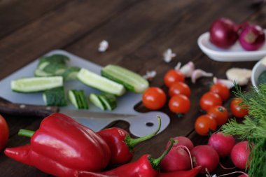 Eski bir ahşap masa üzerinde bir kesme tahtası üzerinde bir salata için taze sebze dilimlenmiş