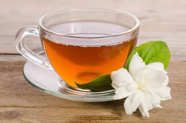 Cam bardak çay ile ahşap masaya Yasemin çiçek