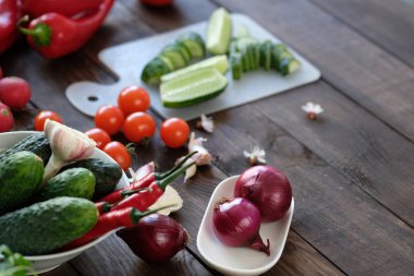 Eski bir ahşap masa üzerinde bir kesme tahtası üzerinde bir salata için taze sebze dilimlenmiş