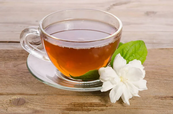 Cam bardak çay ile ahşap masaya Yasemin çiçek