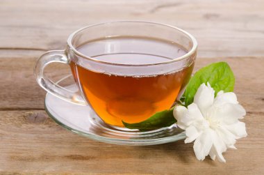 Cam bardak çay ile ahşap masaya Yasemin çiçek