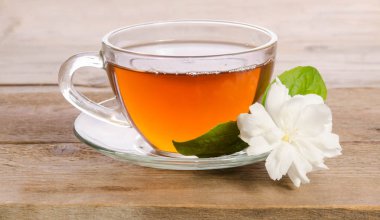 Cam bardak çay ile ahşap masaya Yasemin çiçek