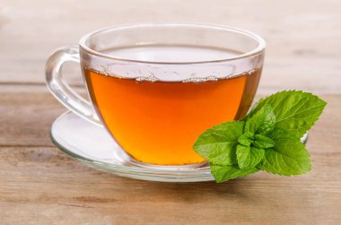 Cam bardak çay nane ile tahta masada bırakır