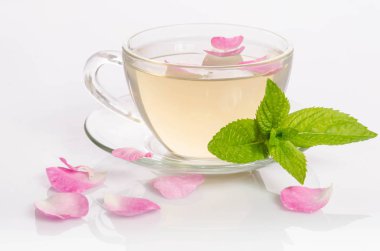 Cam bardak çay nane yaprakları ve gül yaprakları üzerinde masa lambası ile