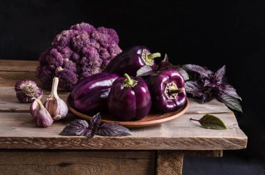 Taze sebze. Koyu mor biber, siyah arka plan üzerine eski rustik ahşap masa üzerinde fesleğen ve sarımsak ile karnabahar bırakır