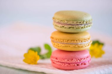 Mavi ahşap masa üzerinde güzel sarı çiçekli Beyaz peçete üzerinde renkli macarons
