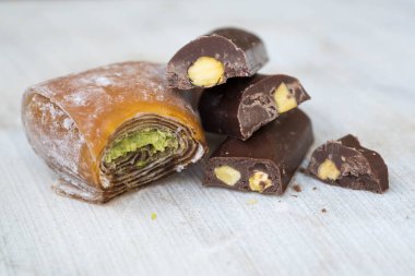 Beyaz ahşap zemin üzerine Antep fıstığı ile Doğu Türk tatlılar. Antep fıstığı ile güzel kokulu baklava, çikolata, tatlılar.