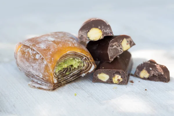 Eastern sweets with pistachios on a white wooden background. Fragrant baklava, chocolate, sweets with pistachios.