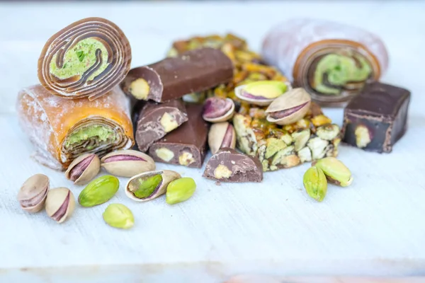 Eastern Turkish sweets with pistachios on a white wooden background. Fragrant baklava, chocolate, sweets with pistachios.