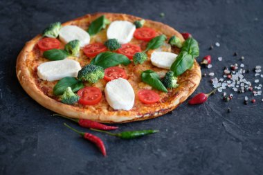 İtalyan pizza Mozzarella peyniri, domates, brokoli, baharat ve taze fesleğen. Siyah taş zemin üzerine pizza