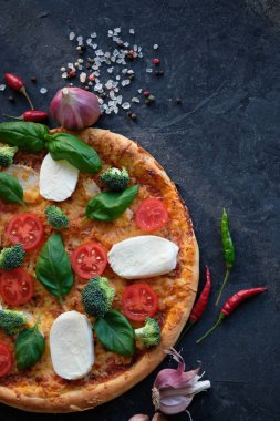 İtalyan pizza Mozzarella peyniri, domates, brokoli, baharat ve taze fesleğen. Siyah taş zemin üzerine pizza