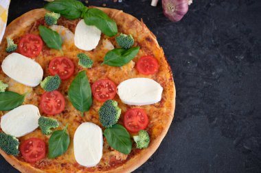 İtalyan pizza Mozzarella peyniri, domates, brokoli, baharat ve taze fesleğen. Siyah taş adam pizzaya