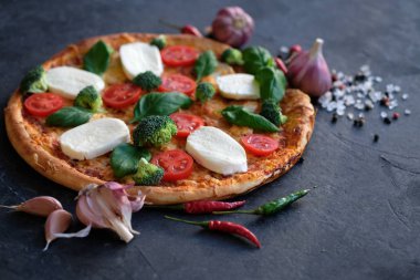 İtalyan pizza Mozzarella peyniri, domates, brokoli, baharat ve taze fesleğen. Siyah taş zemin üzerine pizza