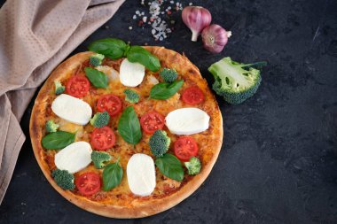 İtalyan pizza Mozzarella peyniri, domates, brokoli, baharat ve taze fesleğen. Siyah taş adam üzerinde yakınındaki, pizza ve mutfak peçete