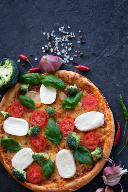 İtalyan pizza Mozzarella peyniri, domates, brokoli, baharat ve taze fesleğen. Siyah taş adam pizzaya