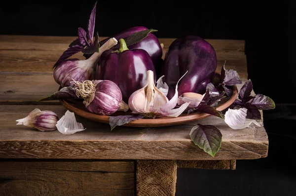 Dark purple peppers with leaves of basil and garlic on old rust — Stock Photo, Image