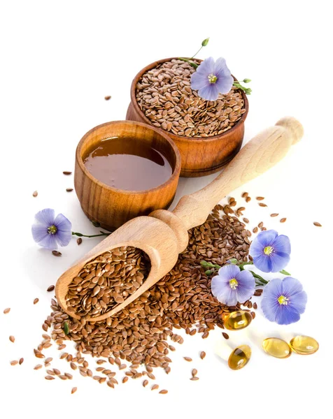 Flax seeds in the wooden scoop, bowl with oil and oil in caps a — Stock Photo, Image