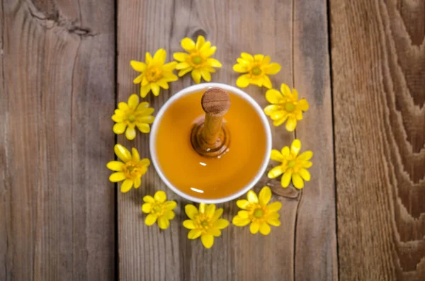 Honung i en skål, strömstare och gula blommor runt det — Stockfoto