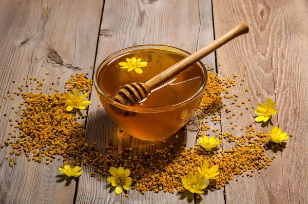 Honung i glasskål, pollen och gula blommor runt den — Stockfoto