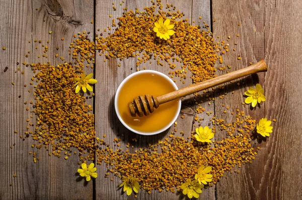 Az üvegtál méz, virágpor és sárga virágok körül — Stock Fotó