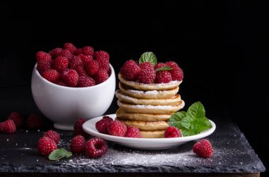 Kase ve siyah artalan üzerinde ahududu ile Pancakes