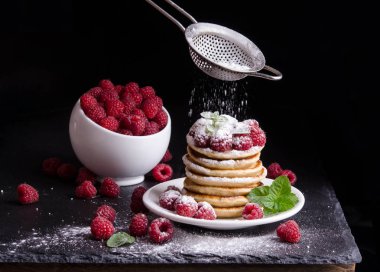Kase ve siyah artalan üzerinde ahududu ile Pancakes