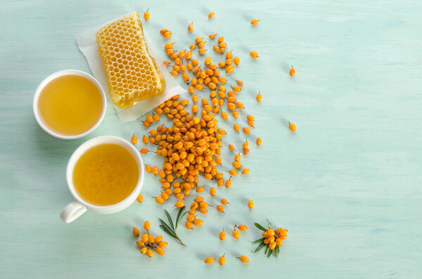 Sea buckthorn , honey and cup of  tea with Sea buckthorn on blue