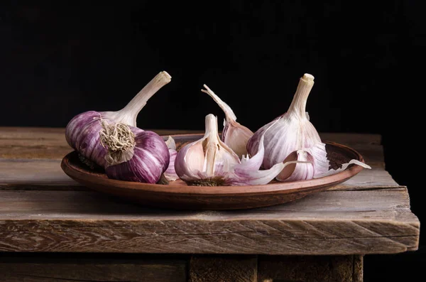 Garlic in the plate on old wooden table  and black background — Stock Photo, Image