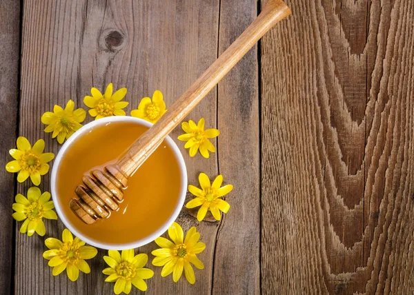 Honung i glas skål och gula blommorna runt det på trä b — Stockfoto