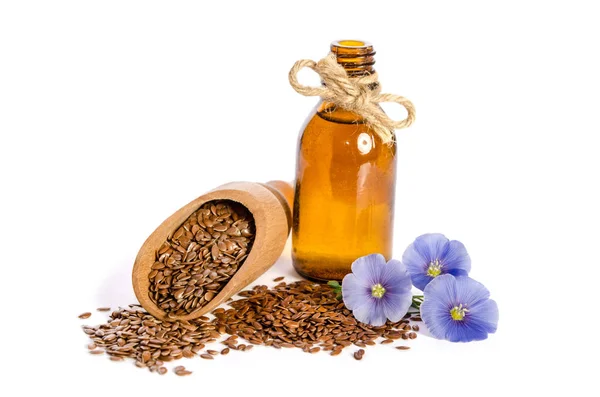 Graines de lin dans la cuillère en bois, bouteille d'huile et de fleurs de lin — Photo