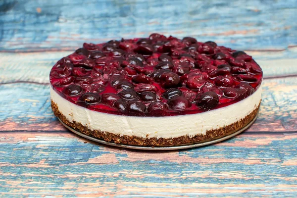 Cold cheesecake with cherry jelly on table