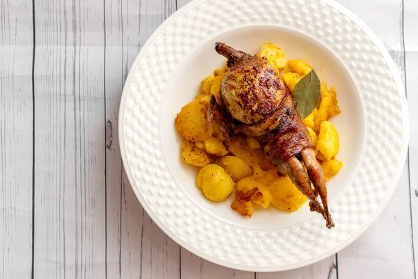 Roasted quail wrapped in bacon and sauteed potatoes Stock Image