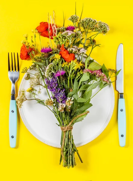 Beyaz tabakta düz bir çiçek buketi. Temiz yemek, paleo, biyohack, bitkisel tıp konsepti