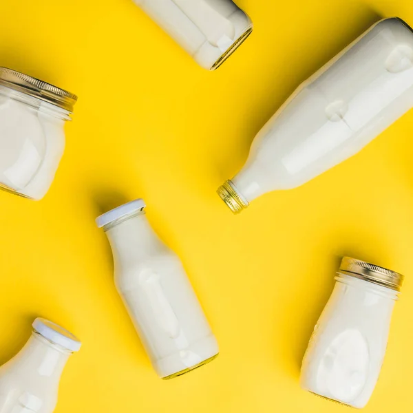 Verschillende flessen van melk op gele achtergrond — Stockfoto
