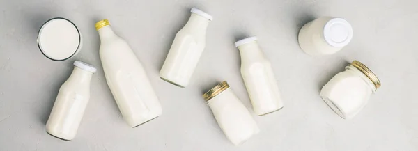 Várias garrafas de leite no fundo de concreto cinza — Fotografia de Stock