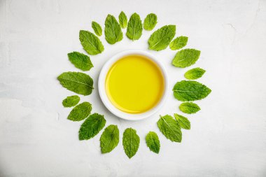 Zeytin yağı ve nane yaprakları beyaz taş zemin üzerine