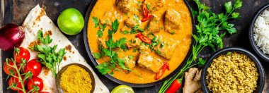 Geleneksel köri ve malzemelerin koyu arka plan üzerine. Köri, limon, zencefil, biber, naan ekmek, pirinç, kuskus, otlar ve baharatlar yat