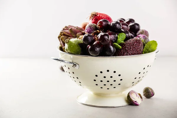 Purple fruits and vegetables in colander - space for text — Stock Photo, Image