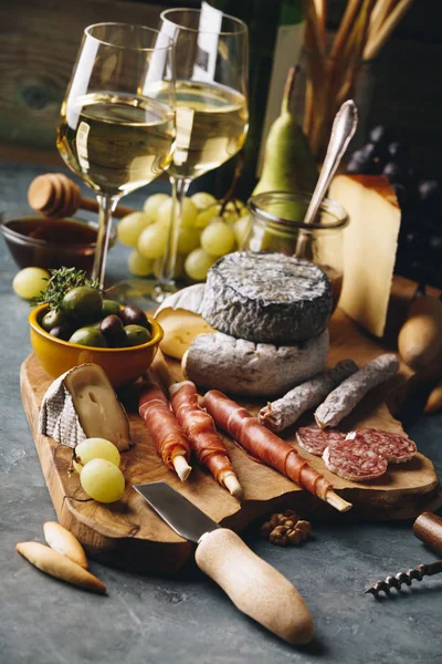 Vino blanco con surtido de charcutería sobre fondo de piedra — Foto de Stock